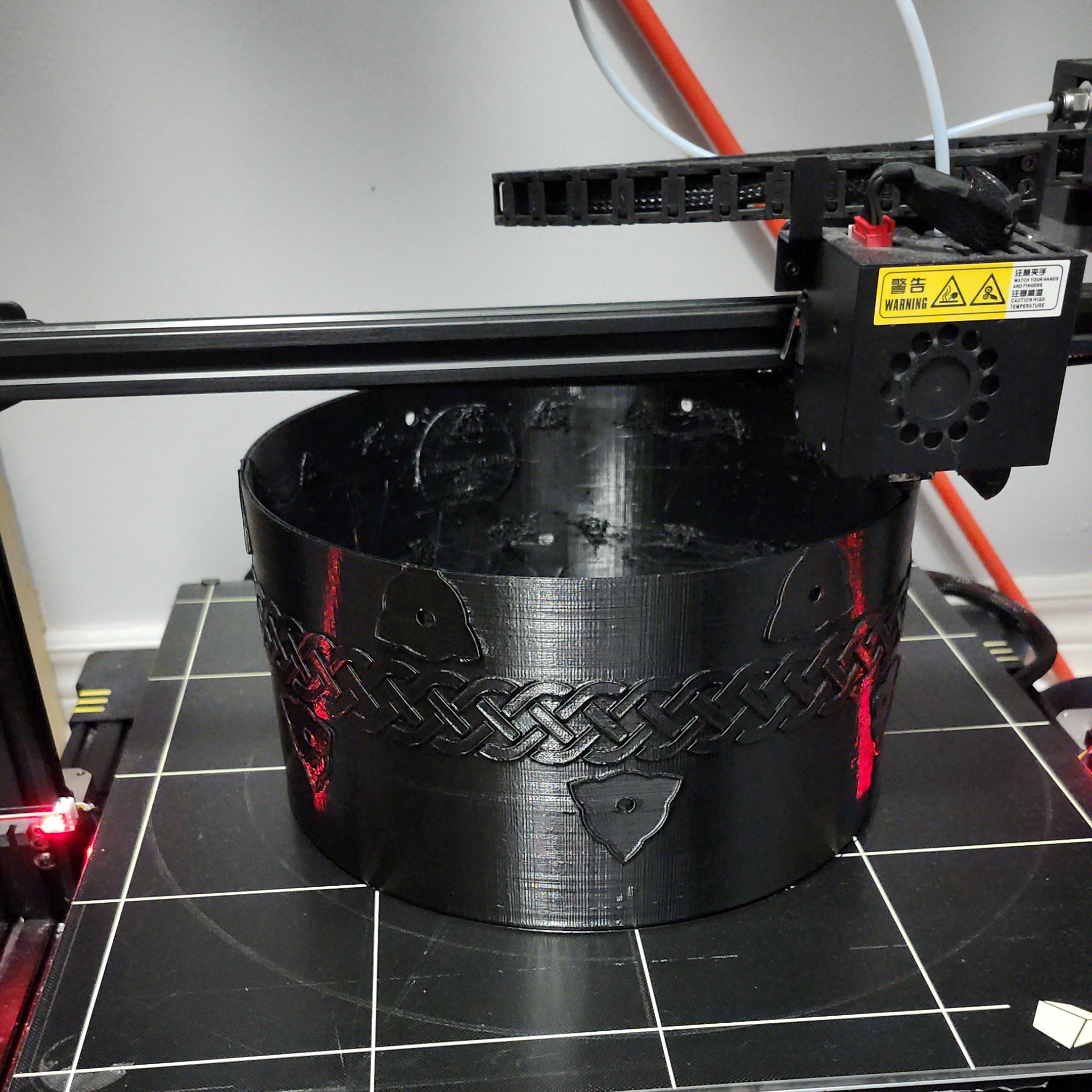 Full-size tom shell emerging from the large-format 3D printer — black with dramatic red highlights